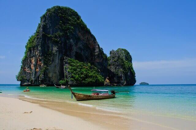 Um barco ancorado em frente de uma das famosas cársticas (formações rochosas) perto de Phra Nang Beach, em Krabi, na Tailândia.