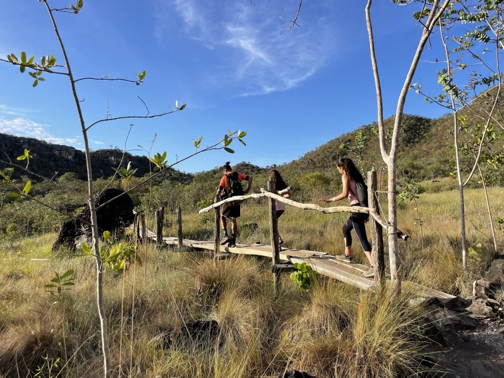 Uma imagem de três pessoas atravessando uma ponte de madeira, curtindo férias em família